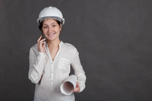 Young female engineer in a protective helmet talking on the phone — Stock Photo, Image