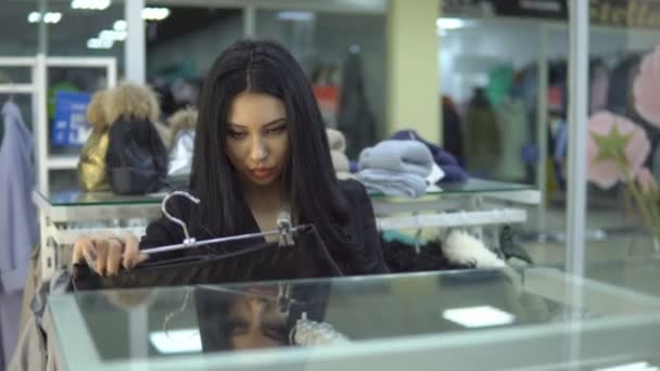 Jonge vrouw op zoek naar een aanduiding van de prijs bij een winkelcentrum of kledingwinkel. — Stockvideo