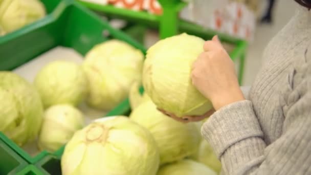 Junge Frau in der Gemüseabteilung eines Supermarktes wählt Kohl — Stockvideo
