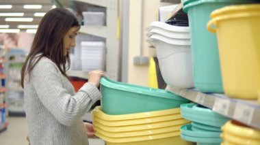 Ev bahçe için Dükkanı. Genç bir kadın büyük bir plastik leğen kemiği seçer