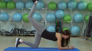Fitness kavramı. Genç bir kadın bacaklarını ile floplar yapıyor. Kalça egzersizleri