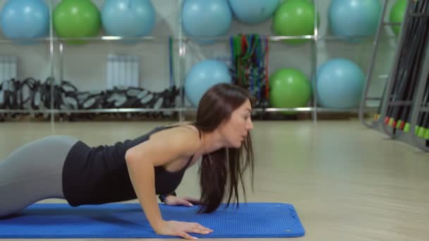 Фитнес-центр. Молодая женщина делает упражнения на гимнастическом коврике — стоковое видео