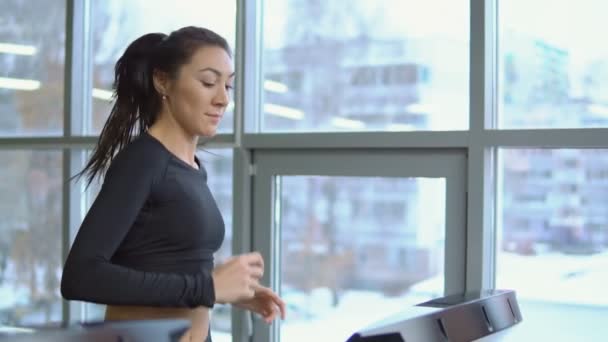 Fitness koncepció. Fiatal gyönyörű nő a futópadon a tornateremben — Stock videók