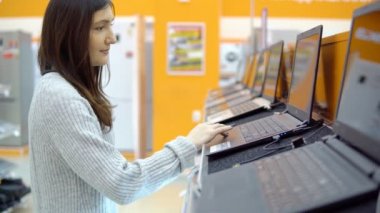 Ev aletleri mağazası. Genç kadın bir laptop seçer