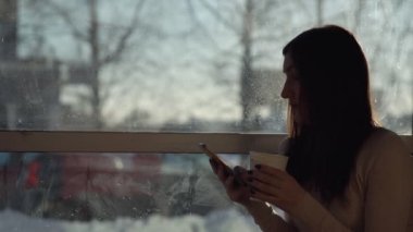 Genç kadın ile bir telefon ve içki cam kenarında bir kafede. Öğle yemeği molası