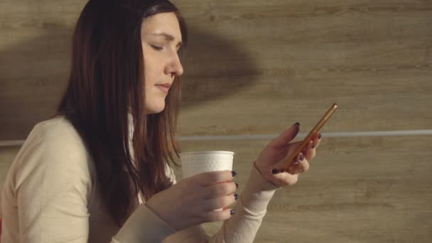 Fiatal nő kávézóban itallal és telefon. Ebédszünet — Stock videók
