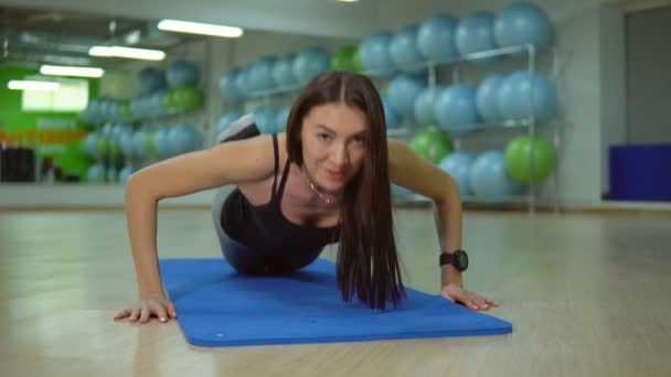 Concepto fitness. Mujer joven haciendo ejercicios en una colchoneta de gimnasio — Vídeos de Stock