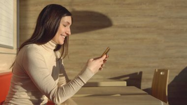 Telefon ile kafede oturan genç esmer kadın. sanal iletişim