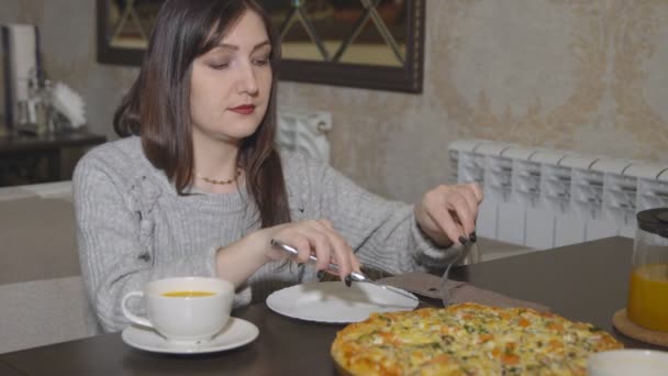 Pizzería. Mujer joven toma una rebanada de pizza con cubiertos — Vídeos de Stock