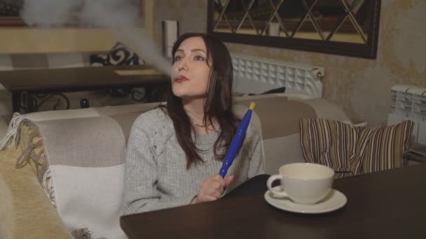 Mujer joven en un café fumando una cachimba — Vídeos de Stock