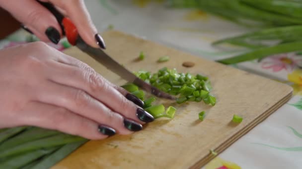 Kadın bir ahşap kesme tahtası üzerinde yeşil soğan doğrama — Stok video