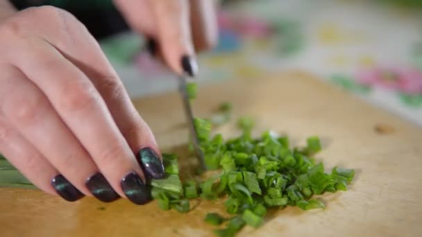Жінка нарізає зелену цибулю на дерев'яній обробній дошці — стокове відео