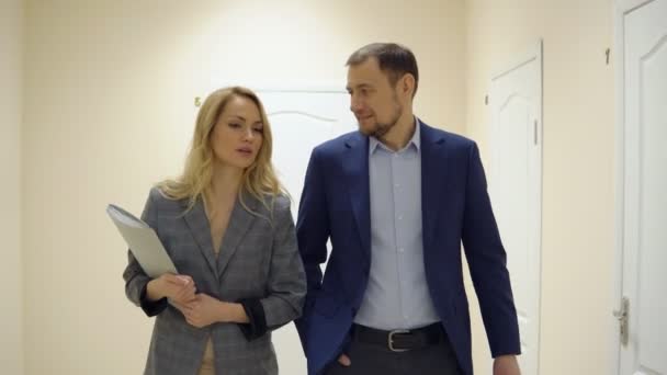 Business kvinna och en man är promenader längs korridoren och talar — Stockvideo