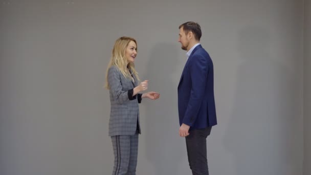 Fröhliche Frau und Mann in Business-Anzügen tanzen auf grauem Hintergrund. — Stockvideo