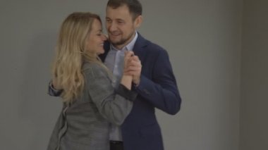 Adam ve bir kadın slow bir dans ofiste gri artalan üzerinde dans ediyor.