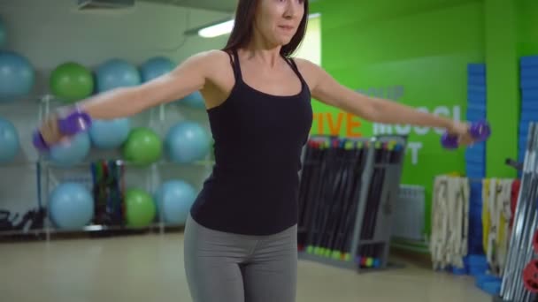 Concept van een gezonde levensstijl. Jonge vrouw met halters in de sportschool — Stockvideo