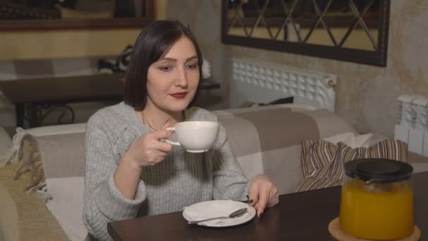 Bruna donna in un caffè bere tè vitaminico — Video Stock