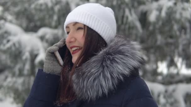 La joven está hablando por teléfono en el bosque de invierno. Caminar al aire libre — Vídeo de stock