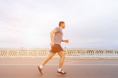 Günbatımında bir çitin yanında nehir üzerinde çalışan yakışıklı bir genç adam.