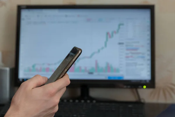 Mano masculina con teléfono en el fondo de la computadora —  Fotos de Stock