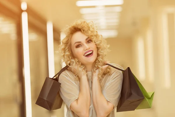 Feliz joven con bolsas de compras en el centro comercial sonriendo . —  Fotos de Stock