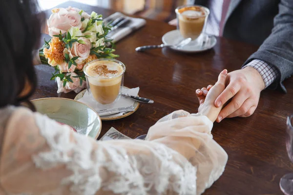 Bride and groom holding hands in restaurant — Stock Photo, Image