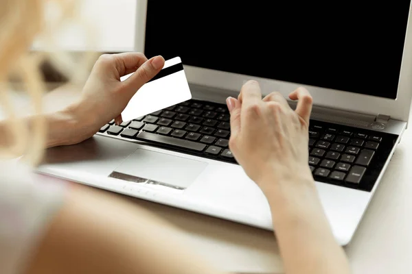 Die Hände einer Frau in Großaufnahme, die eine Kreditkarte hält und die Computertastatur für Online-Einkäufe benutzt. — Stockfoto