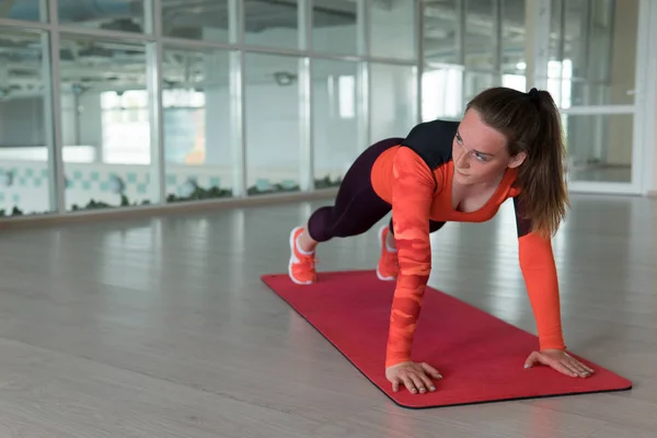 Chica bonita haciendo variación de tablón de ejercicio en el gimnasio — Foto de Stock