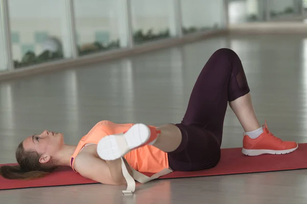 Unga kvinnliga friidrottare i sportkläder gör warm-up på mattan i gymmet med tejp — Stockfoto