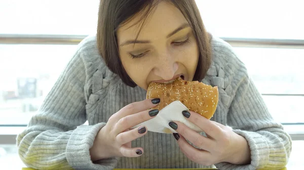 Comida rápida. Jovem com apetite a comer um hambúrguer — Fotografia de Stock