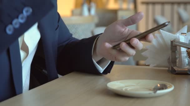 Un joven con un teléfono en un café. Primer plano — Vídeos de Stock