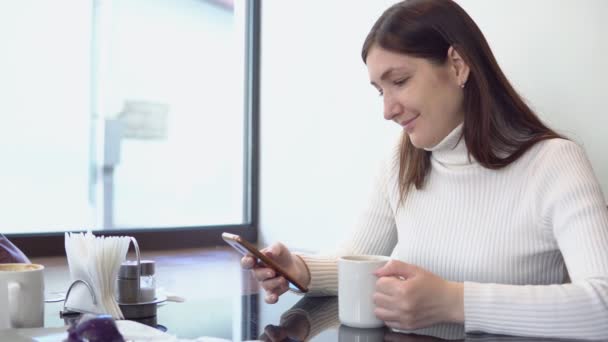 Schöne Frau an einem Cafétisch mit Telefon — Stockvideo