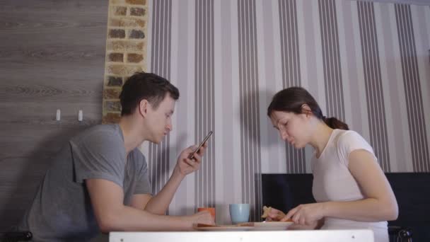 Jonge man met telefoon en vrouw eten aan tafel — Stockvideo