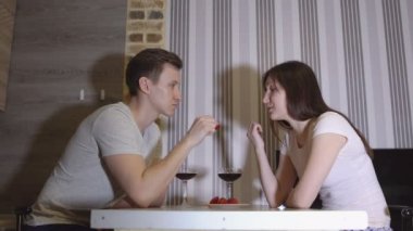 Romantik akşam. Şarap içme ve çilek yeme bir masada genç Çift