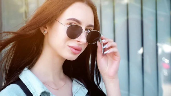 Pretty brunette with long hair takes off black sunglasses — Stock Photo, Image