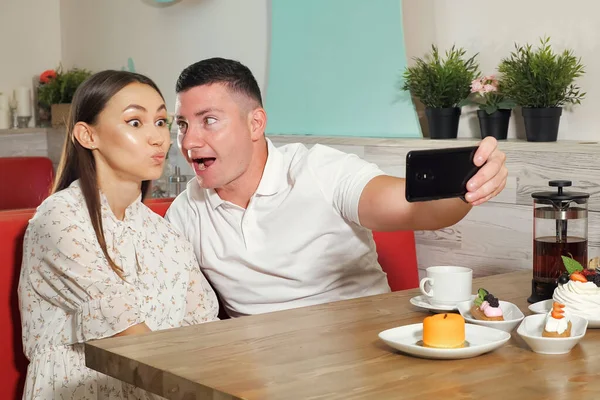 Szczęśliwa para sprawia, że selfie siedzi w serwowany stolik w kawiarni — Zdjęcie stockowe