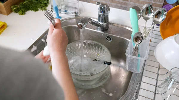 La donna sta lavando le posate con le mani in cucina a casa . — Foto Stock