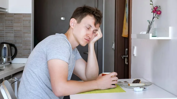 Спящий мужчина выпивает чашку чая, сидя на маленькой кухне в съемной квартире в отпуске . — стоковое фото