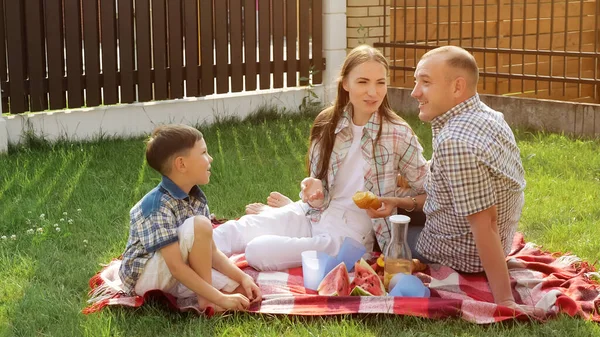 Feliz joven mujer y hombre sentarse con pequeño niño en el césped — Foto de Stock