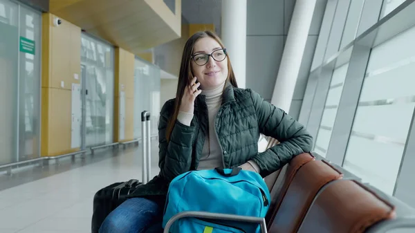 Счастливая женщина разговаривает по мобильному телефону ждет свой рейс в аэропорту . — стоковое фото