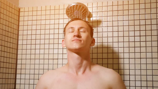 Retrato de un joven tomando una ducha peinándose los pelos con las manos . —  Fotos de Stock