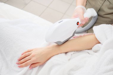 Kozmetik uzmanı modern teknolojiyi kullanarak epilasyon yapıyor.