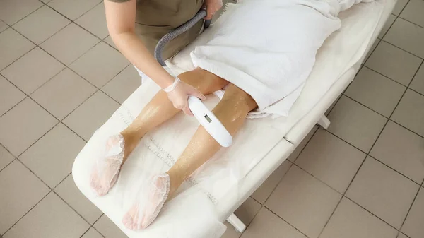 Медсестра робить лазерну епіляцію на нозі дівчини вид зверху — стокове фото
