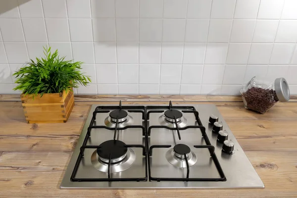 Серебряная газовая плита, расположенная на поверхности деревянной кухни — стоковое фото