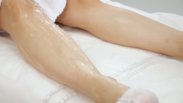 Las manos de mujer aplican gel y deslizan la cabeza láser sobre la pierna gelificada en el centro médico — Vídeo de stock