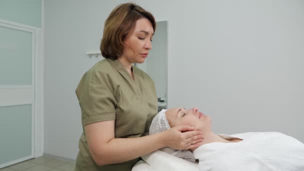 Косметолог делает профессиональный массаж лица вид сбоку — стоковое видео