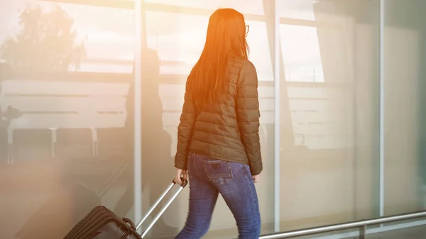 La donna sta camminando nel moderno terminal dell'aeroporto portando la valigia — Foto Stock