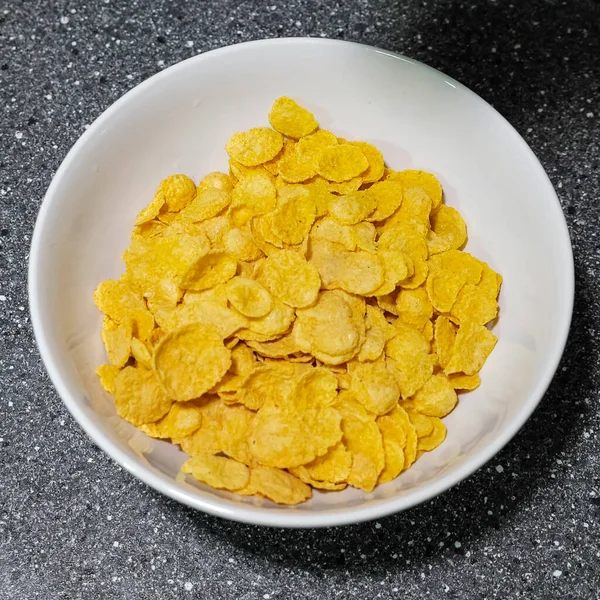 Cornflakes in weißer Schale auf grauem Tisch — Stockfoto