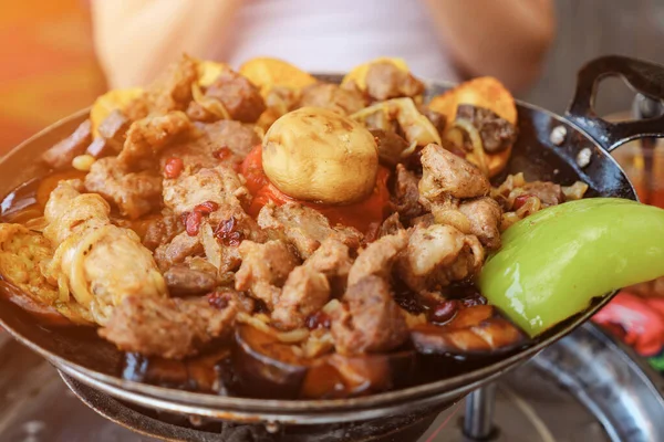 Mulher comendo carne com legumes servidos em frigideira no restaurante, close-up . — Fotografia de Stock