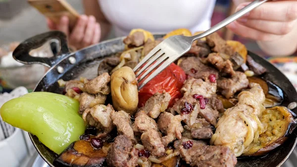 Mulher comendo carne com legumes servidos em frigideira no restaurante, close-up . — Fotografia de Stock